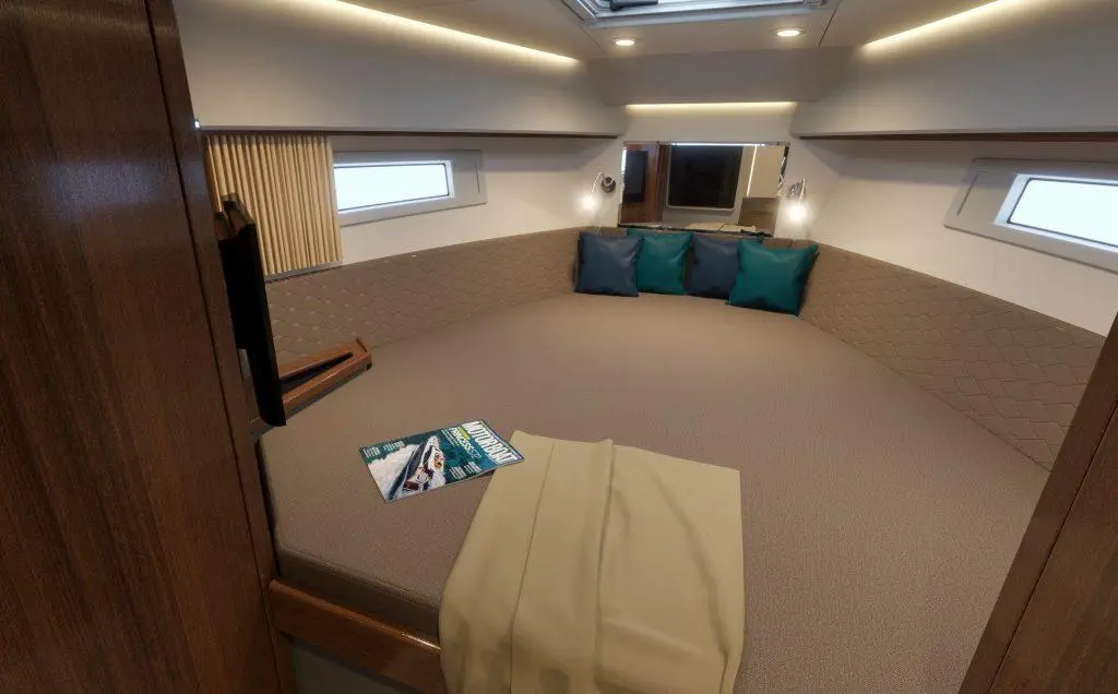 Modern boat cabin with large bed, teal cushions, magazine on the floor, and natural light from windows. Comfortable interior design.